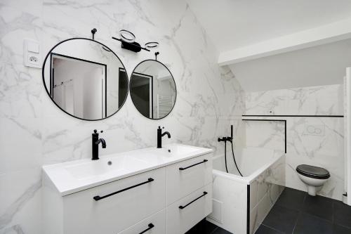 ein weißes Badezimmer mit einem Waschbecken und einem Spiegel in der Unterkunft Pick A Flat's Apartment in La Chapelle - Impasse du Curé in Paris