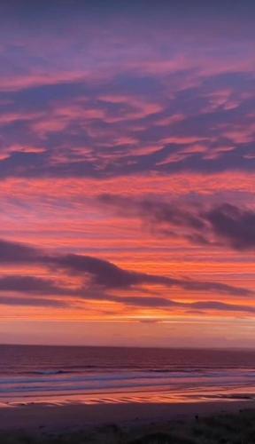 a sunset over the ocean with a cloudy sky at Wild Meadow Huts in Doolin