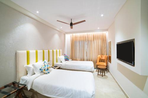 a hotel room with two beds and a flat screen tv at The Beacon Hotel Visakhapatnam in Visakhapatnam