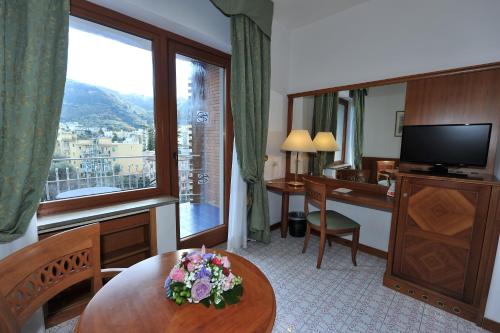 Cette chambre d'hôtel dispose d'une table et d'une grande fenêtre. dans l'établissement Grand Hotel Cesare Augusto, à Sorrente