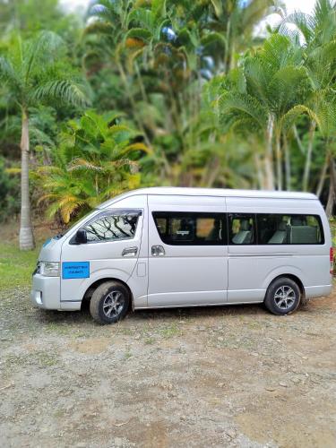 a white van parked in front of some palm trees at Leiko Guest House in Vacoas