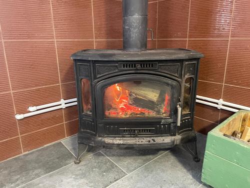 a black stove with a fire in a room at Pensiunea Vis Alpin Belis in Beliş