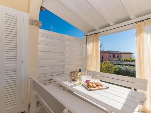 un porche blanco con una mesa con comida y una ventana en Apartment Agrifoglio by Interhome, en Casa Tamponi