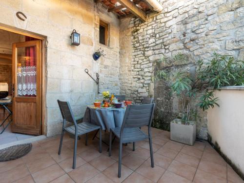 a table and chairs on a patio with a stone wall at Apartment Belles Pierres by Interhome in Calvisson