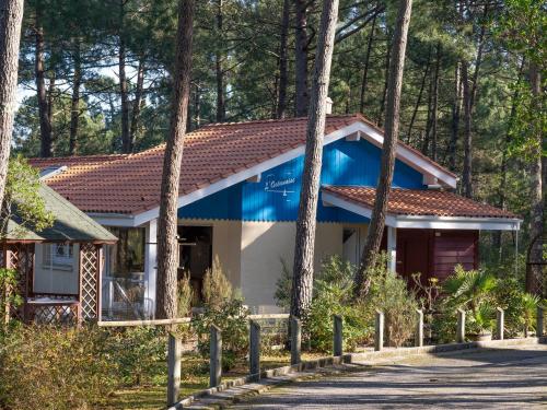 dom w lesie z niebieskim dachem w obiekcie Holiday Home Golf Loisirs-1 by Interhome w mieście Lacanau-Océan