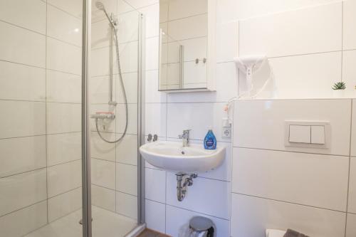 a white bathroom with a sink and a shower at Apartments am Lindengraben in Emden