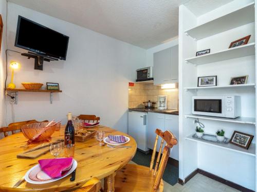 eine Küche und ein Esszimmer mit einem Holztisch in der Unterkunft Apartment Les Mousquetons-19 by Interhome in La Toussuire