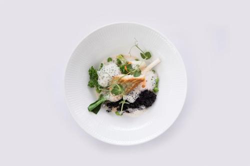 a white plate with food on a white table at Melsted Badehotel in Gudhjem