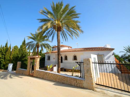 uma casa com uma palmeira atrás de uma cerca em Villa Luisa by Interhome em Calpe