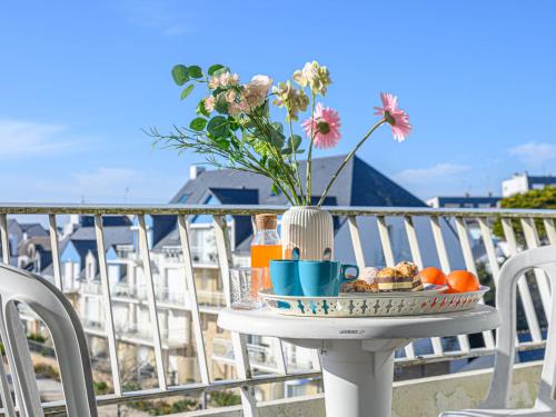 a table with a tray of food and flowers on a balcony at Apartment Kérabus-1 by Interhome in Quiberon