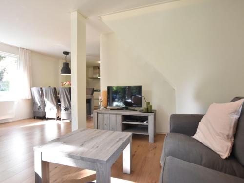 ein Wohnzimmer mit einem Sofa, einem Tisch und einem TV in der Unterkunft Chalet Oosterduinen by Interhome in Norg