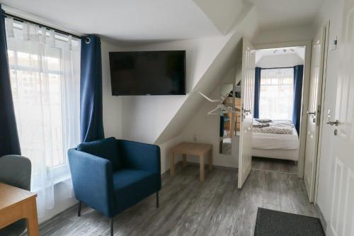 a living room with a blue chair and a bedroom at Apartments am Lindengraben in Emden