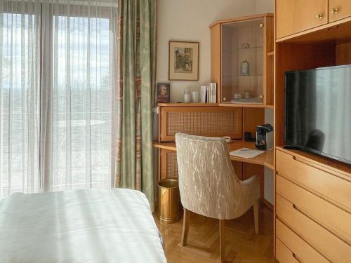 een slaapkamer met een bureau, een televisie en een stoel bij Landhaus zu Kürenberg in Bergham