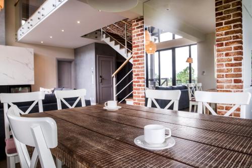 a dining room with a wooden table and white chairs at Hotel SPA Dr Irena Eris Wzgórza Dylewskie - Siedliska in Wysoka Wieś