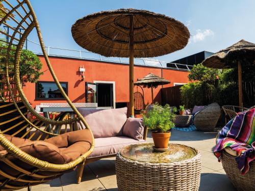 a patio with a chair and an umbrella at MOB HOTEL Paris Les Puces in Saint-Ouen