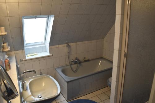 La salle de bains est pourvue d'une baignoire, d'un lavabo et d'une fenêtre. dans l'établissement Ferienhaus Heideglück, à Bad Fallingbostel