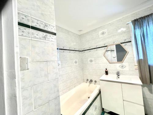 Baño blanco con bañera y lavamanos en Fully Private 3 bedroom house with free parking, en Fairfield
