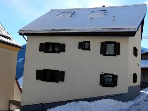a white building with black windows in the snow at Apartment Ferienhaus Tgioc by Interhome in Obervaz
