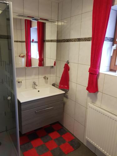 a bathroom with a sink and a red shower curtain at Apartment Curly in Scheyern