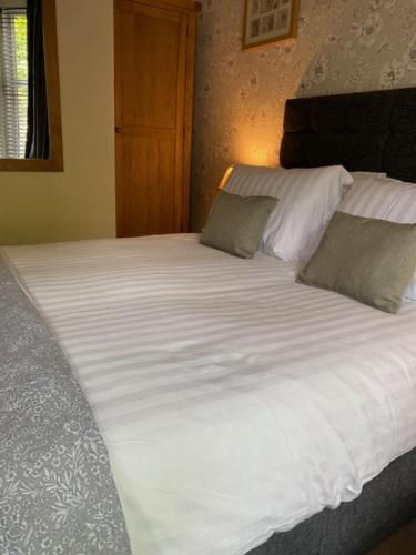 a large bed with white sheets and pillows at Melbourne Guest House in Bowness-on-Windermere