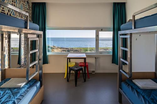 Cette chambre avec vue sur l'océan dispose de lits superposés et d'une table. dans l'établissement Stayokay Hostel Terschelling, à West-Terschelling