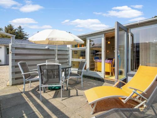 a patio with chairs and a table and an umbrella at Apartment Genadij - 1km from the sea in Western Jutland by Interhome in Vejers Strand