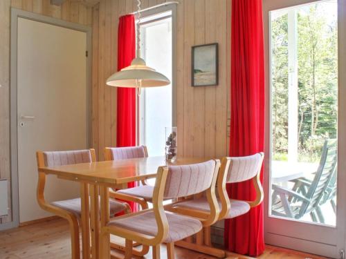 - une salle à manger avec des rideaux rouges, une table et des chaises dans l'établissement Holiday Home Gerarda - 4km from the sea in NE Jutland by Interhome, à Læsø