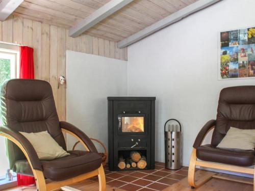 two chairs in a living room with a fireplace at Holiday Home Gerarda - 4km from the sea in NE Jutland by Interhome in Læsø
