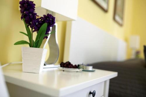 a white table with a vase with purple flowers on it at Seawall Holiday Home in Salerno