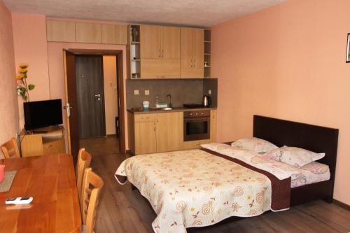 a bedroom with a bed and a table and a kitchen at Studio Manushev in Sandanski