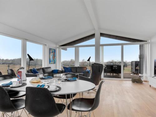 een eetkamer met tafels, stoelen en ramen bij Holiday Home Gerniot - 500m from the sea in NE Jutland by Interhome in Frederikshavn
