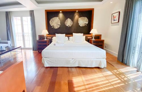 a bedroom with a large white bed and wooden floors at Hotel MR Les Rotes in Denia