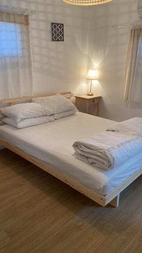 a white bed in a bedroom with a lamp on it at בין יער לים in Shlomi