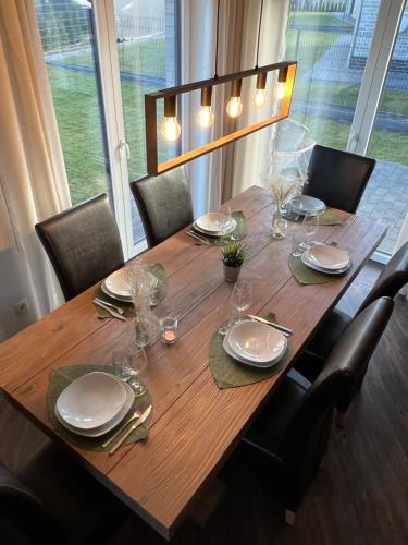 a wooden table with chairs and plates and glasses at Ferienhaus Bella Haus am Harkebrügger See in Barßel