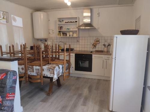 une cuisine avec une table, des chaises et un réfrigérateur dans l'établissement Appartement Le Paradou à Besse, à Besse-et-Saint-Anastaise