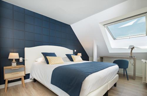 a bedroom with a large bed and a window at Les Chants d'Ailes - Hôtel Face Mer in La Turballe