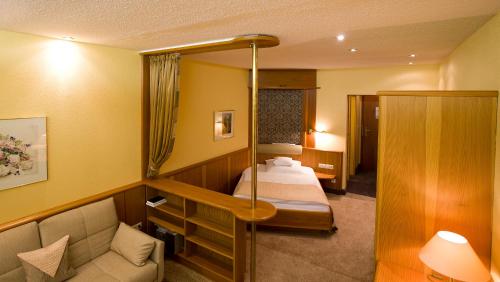 a hotel room with two beds and a couch at Wellness-& Nationapark Hotel Schliffkopf, BWSC in Baiersbronn