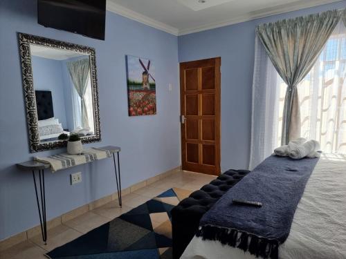 a bedroom with a bed and a mirror and a window at Danrit Guesthouse - Uncapped wifi in Roodepoort