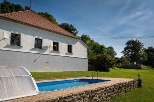 a house with a swimming pool next to a stone wall at Holiday home in Bezděkov/Chotěbor 1393 in Bezděkov