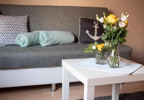 una sala de estar con sofá y un jarrón de flores sobre una mesa en Ferienwohnung in Bitterfeld-Wolfen, en Große Mühle