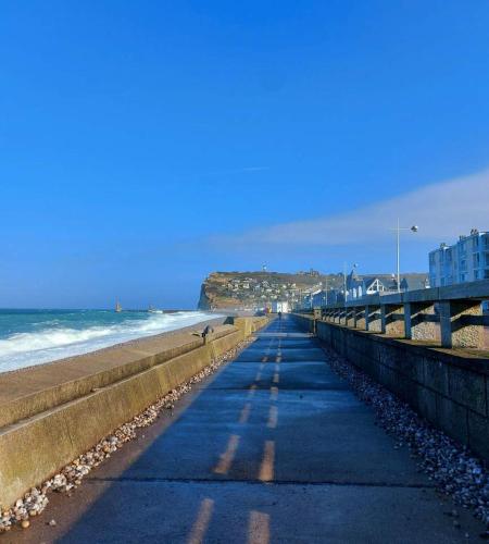 a walkway along a beach with the ocean and buildings at Les Gîtes Panorama et Perle Vue Mer in Fécamp