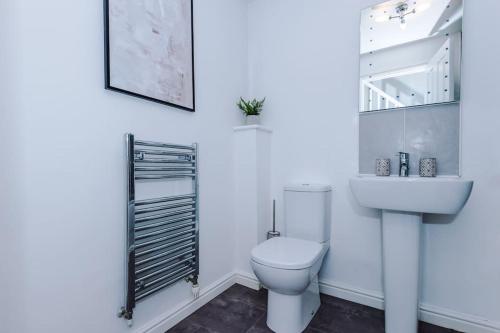 Baño blanco con aseo y lavamanos en Lovely three bed home Manchester, en Heywood