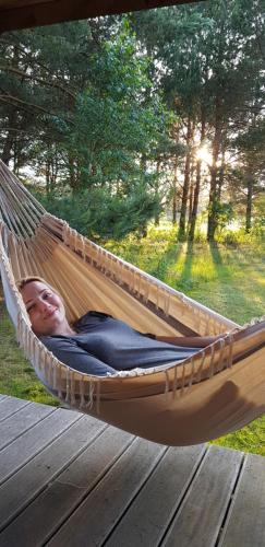 a woman laying in a hammock on a deck at Maciejówka Borki 33 in Borki