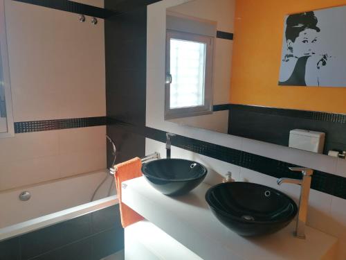 een badkamer met 2 zwarte wastafels en een bad bij Sueños de Levante in Cádiz