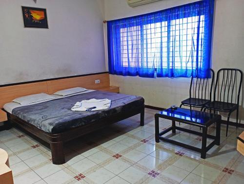 a bedroom with a bed and a chair and a window at STAYMAKER Hotel Ratna Palace in Bijāpur