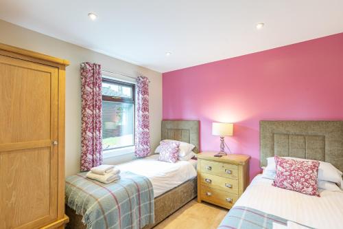 two beds in a bedroom with pink walls and a window at Birch Lodge 20 with Hot Tub in Newton Stewart