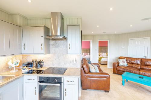 a kitchen and living room with a leather couch at Birch Lodge 20 with Hot Tub in Newton Stewart