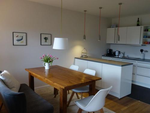 cocina con mesa de madera y sillas blancas en Ferienwohnung Yachthafen - Fördeblick, Glück 2, en Glücksburg