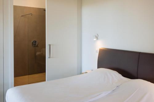 a bedroom with a bed and a glass shower at Landgoed Moerslag in Sint Geertruid