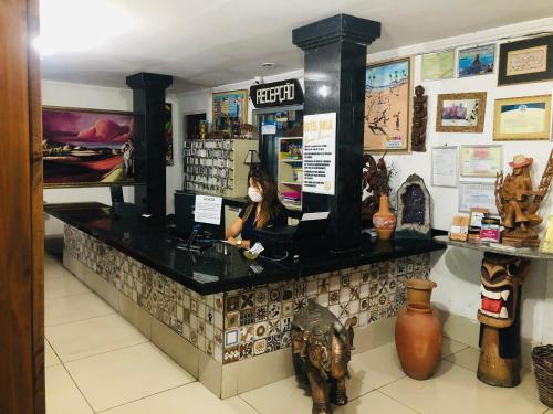 a woman sitting at a counter in a store at Hotel Orla Guest House in Petrolina